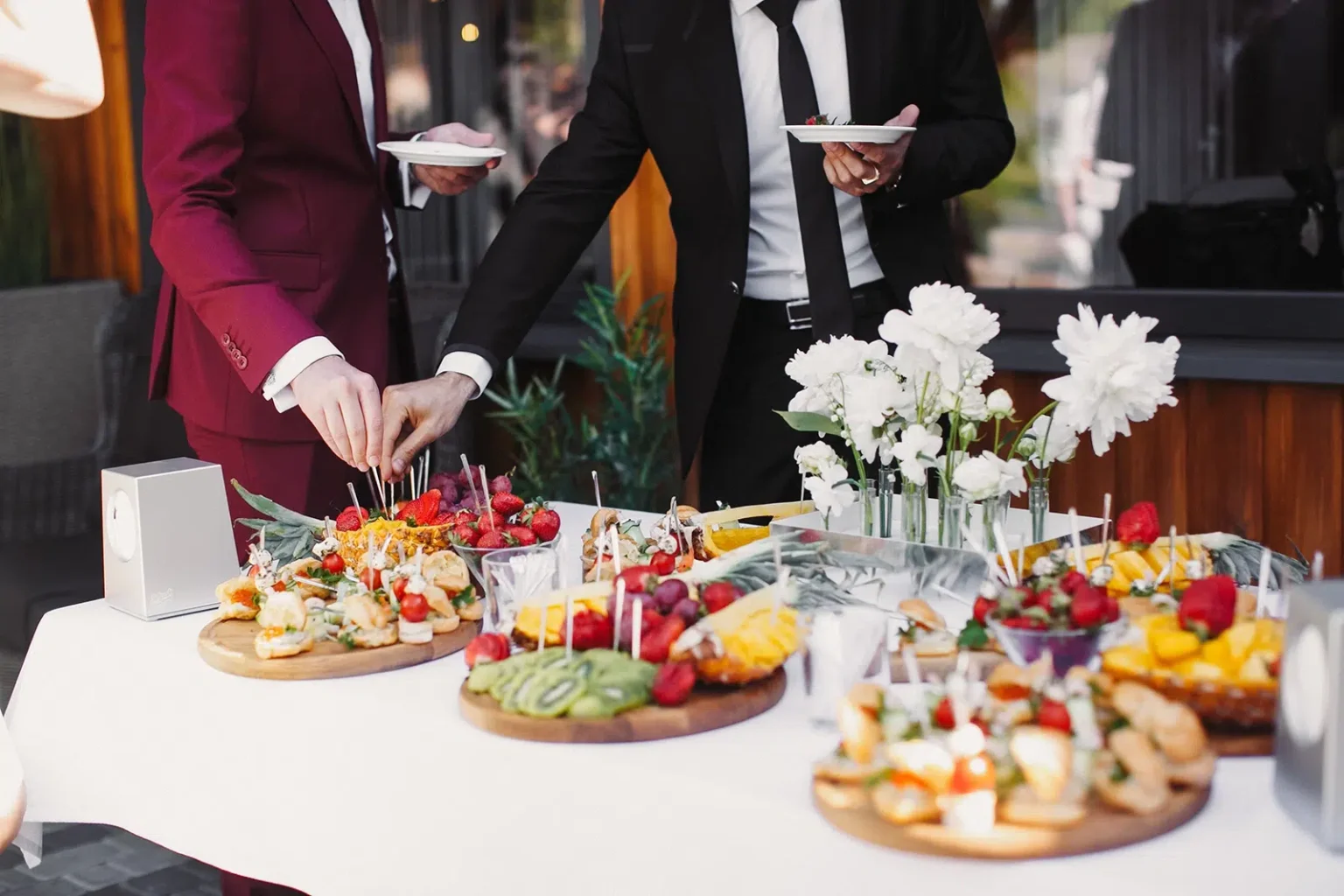 A well-dressed couple help themselves to beautifully presented Funeral Wake Catering In Melbourne prepared by White Knight Catering Services