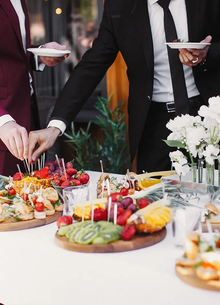 A well-dressed couple help themselves to beautifully presented Funeral Wake Catering In Melbourne prepared by White Knight Catering Services
