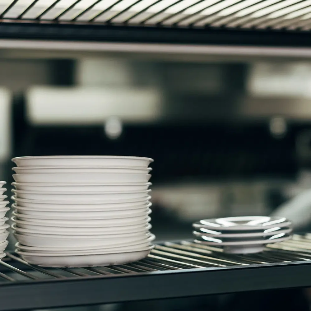 Professional Catering Equipment And Logistics Services in Melbourne, such as these white dinner plates stacked ready for meal service